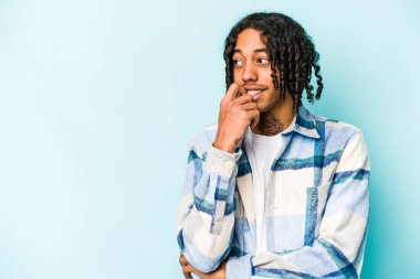 Genç Afrikalı Amerikalı bir adam mavi arka planda izole edilmiş rahat bir şekilde bir şeyin fotokopi odasına baktığını düşünüyor..