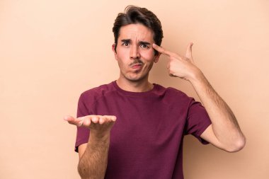 Beyazlı genç bir adam bej arka planda izole edilmiş ve elinde bir ürün var..