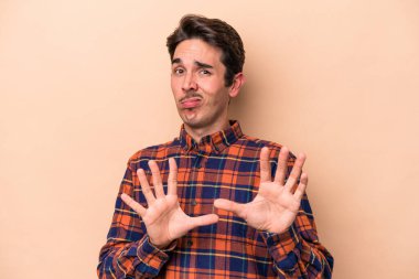 Beyazlı genç bir adam bej arka planda izole edilmiş. İğrenme belirtisi gösteren birini reddediyor..