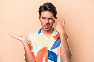 Beyazların arka planında izole edilmiş genç beyaz bir adam işaret parmağıyla hayal kırıklığı jesti yapıyor..