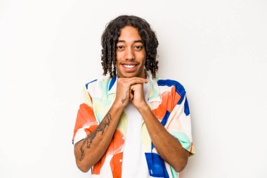 Beyaz arka planda izole edilmiş genç Afrikalı Amerikalı ellerini çenesinin altında tutuyor ve mutlu bir şekilde yan tarafa bakıyor..
