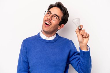 Beyaz arka planda izole edilmiş bir ampul tutan genç beyaz bir adam.