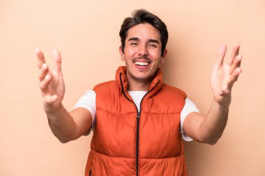 Beyazlı genç bir adam bej arka planda izole edilmiş bir şekilde zaferi veya başarıyı kutluyor. Şaşırmış ve şok olmuş..