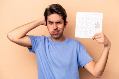 Beyazların arka planında izole edilmiş bir yapboz tutan genç beyaz adam şok geçiriyordu..