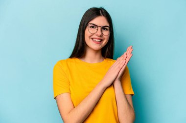 Mavi arka planda izole edilmiş genç beyaz kadın enerjik ve rahat hissediyor, ellerini ovuşturuyor..