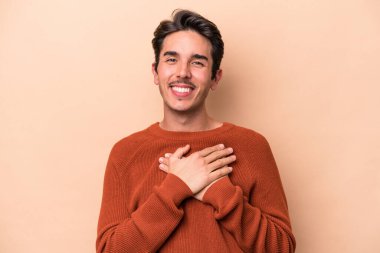 Beyazların arka planında izole edilmiş genç beyaz bir adam dost ifadesine sahip, avuçlarını göğsüne bastırıyor. Aşk konsepti.