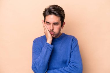 Bej arka planda izole edilmiş beyaz bir genç. Sıkılmış, yorgun ve dinlenmeye ihtiyacı var..