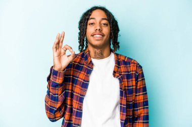 Genç Afrikalı Amerikalı adam mavi arka planda izole edilmiş neşeli ve kendinden emin..