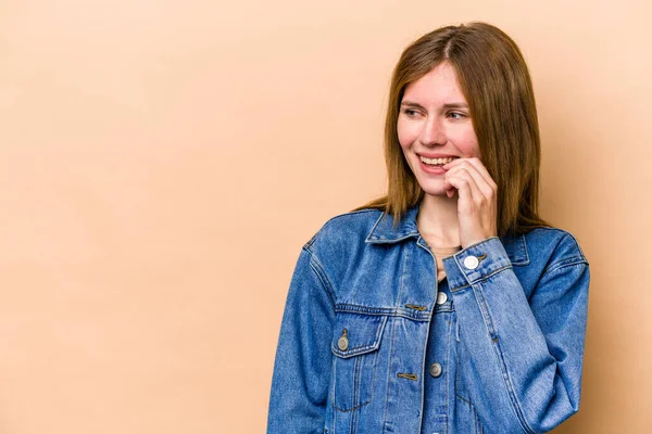 Young English woman isolated on beige background relaxed thinking about something looking at a copy space.