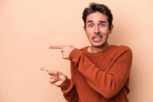 Jonge Blanke Man Geïsoleerd Beige Achtergrond Geschokt Wijzend Met Wijsvingers — Stockfoto