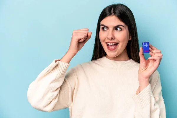 Giovane Donna Caucasica Possesso Una Batteria Isolata Sfondo Blu Alzando — Foto Stock