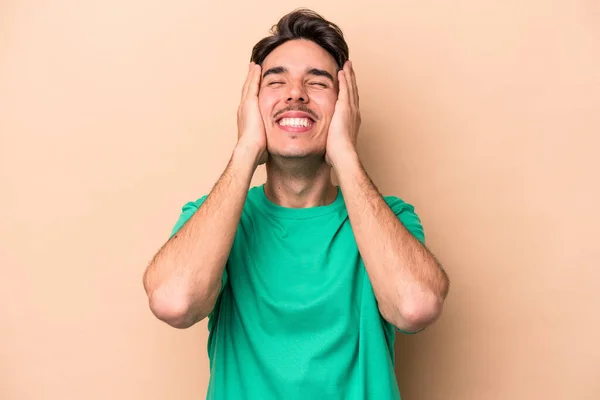 Young Caucasian Man Isolated Beige Background Laughs Joyfully Keeping Hands — Stock Photo, Image