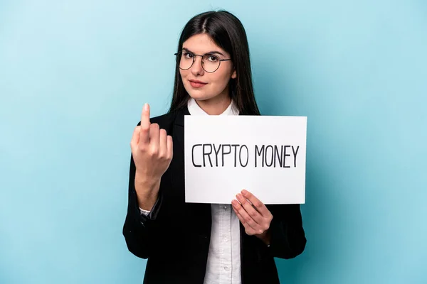Young caucasian business woman holding a crypto money placard isolated on blue background pointing with finger at you as if inviting come closer.