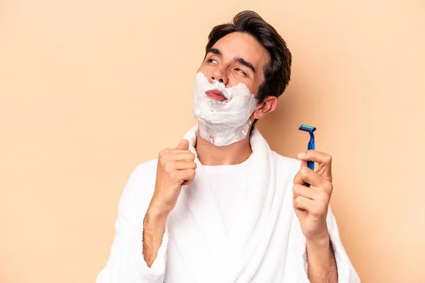 Young Caucasian Man Shaving His Beard Isolated Beige Background Looking — Stock Photo, Image