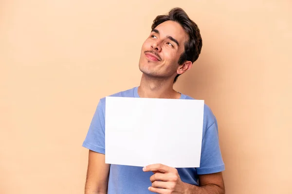 Junger Kaukasischer Mann Mit Einem Plakat Auf Beigem Hintergrund Das — Stockfoto