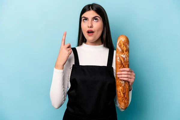 年轻的面包师拿着一块面包 夹在蓝色的背景上 上边是张着嘴的白面包 — 图库照片
