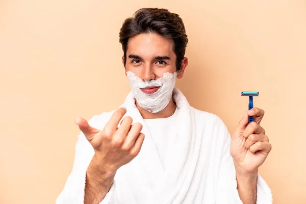 Young Caucasian Man Shaving His Beard Isolated Beige Background Pointing — Stock Photo, Image