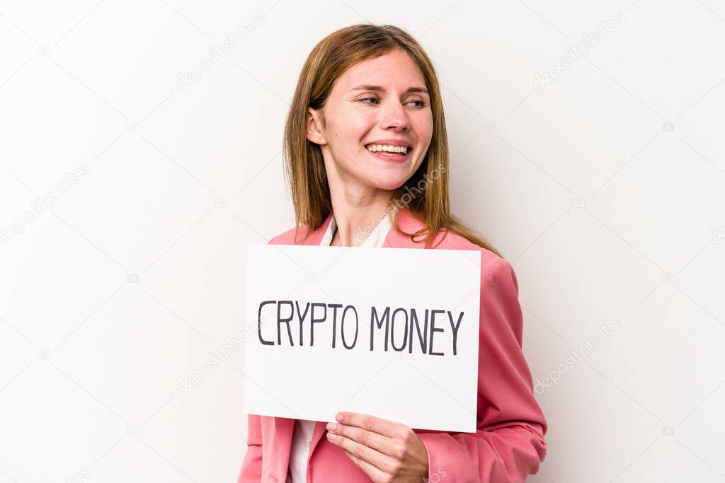 Young English business woman holding a crypto money placard isolated on white background looks aside smiling, cheerful and pleasant.