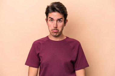 Beyazlı genç bir adam bej arka planda izole edilmiş üzgün, ciddi yüzlü, mutsuz ve hoşnutsuz..