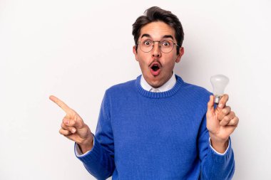Beyaz arka planda izole edilmiş bir ampul tutan genç beyaz bir adam...