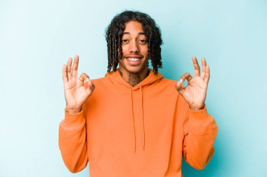 Genç Afrikalı Amerikalı adam mavi arka planda izole edilmiş neşeli ve kendinden emin..