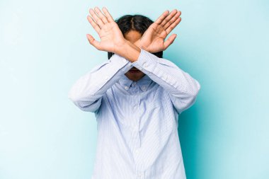 Genç Afrikalı Amerikalı adam mavi arka planda izole edilmiş iki kolu çapraz tutuyor, inkar kavramı.