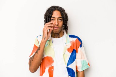 Genç Afrikalı Amerikalı adam beyaz arka planda izole edilmiş, parmakları dudaklarında bir sır saklıyor..