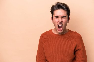 Beyazlı genç bir adam bej arka planda izole edilmiş çok kızgın, öfkeli, hayal kırıklığına uğramış.