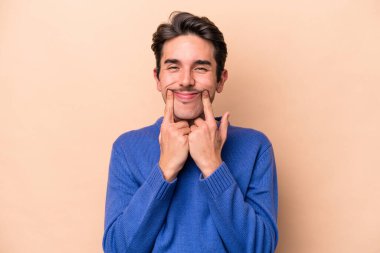 Beyazlı genç bir adam bej arka planda iki seçenek arasında kuşkulanıyor..