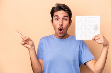 Beyazların arka planında izole edilmiş bir yapboz tutan genç beyaz adam...