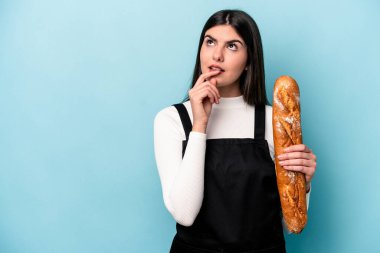 Genç fırıncı Kafkas elinde mavi arka planda izole edilmiş bir somun ekmek tutuyor rahatlamış bir şeyin fotokopi odasına baktığını düşünüyor..