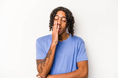 Beyaz arka planda izole edilmiş genç Afrikalı Amerikalı adam esniyor. Ağzını eliyle kapatan yorgun bir hareket sergiliyor..
