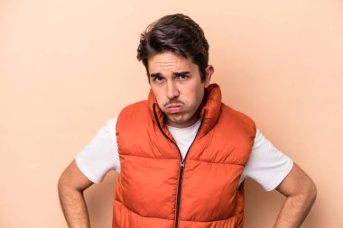 Beyazlı genç bir adam bej arka planda izole edilmiş üzgün, ciddi yüzlü, mutsuz ve hoşnutsuz..