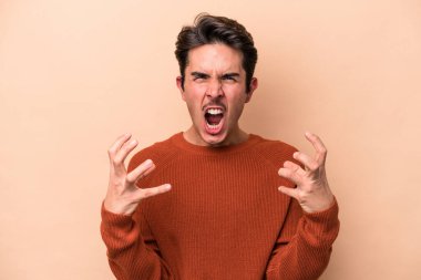 Beyazlı genç adam bej arka planda izole edilmiş öfkeyle bağırıyor..