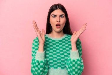 Pembe arka planda izole edilmiş genç beyaz kadın şaşırmış ve şok olmuş..