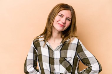 Genç İngiliz kadın bej arka planda izole mutlu, güler yüzlü ve neşeli.