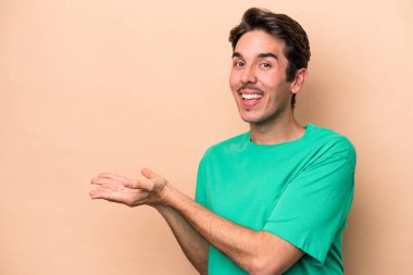 Beyaz tenli genç, bej arka planda izole edilmiş. Elinde palmiye ağacında bir fotokopi alanı var..