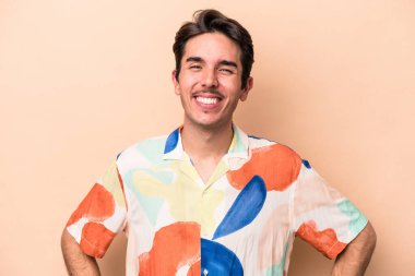 Beyaz tenli genç adam bej arka planda izole edilmiş mutlu, güler yüzlü ve neşeli.