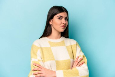 Mavi arka planda izole edilmiş genç beyaz kadın alaycı bir ifadeyle kameraya bakarken mutsuz oluyor..