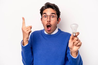 Beyaz arka planda izole edilmiş bir ampul tutan genç beyaz bir adam.