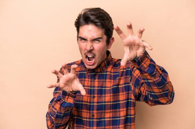 Beyazlı genç adam bej arka planda izole edilmiş gergin elleriyle çığlık atıyor..