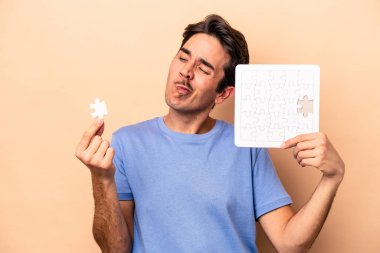 Beyazların arka planında izole edilmiş bir yapboz tutan genç beyaz adam.