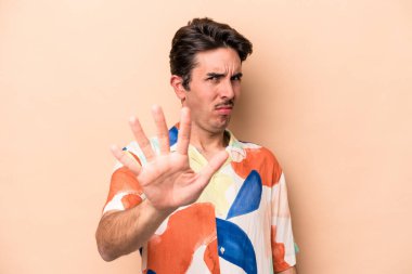 Beyazlı genç bir adam bej arka planda izole edilmiş. İğrenme belirtisi gösteren birini reddediyor..