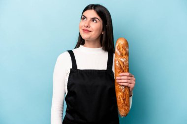 Genç fırıncı Kafkasyalı, mavi arka planda bir somun ekmek tutuyor. Amaçlarına ve amaçlarına ulaşma hayali kuruyor.