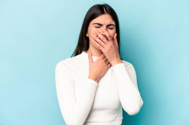 Mavi arka planda izole edilmiş genç beyaz kadın virüs ya da enfeksiyon yüzünden boğazında ağrı hissediyor..