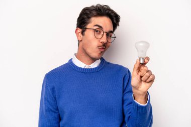 Beyaz arka planda izole edilmiş bir ampul tutan genç beyaz bir adam.