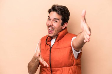 Beyazlı genç adam bej arka planda izole edilmiş kameraya sarıldığı için kendinden emin hissediyor..