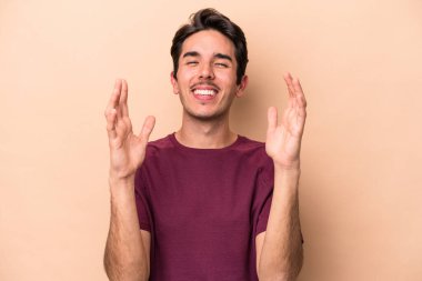 Beyaz tenli genç adam bej arka planda izole edilmiş. Kahkahalar atıyor..