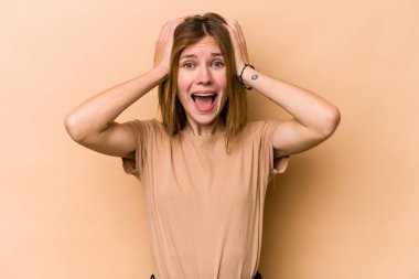Genç İngiliz kadın bej arka planda izole edilmiş bağırıyor, çok heyecanlı, tutkulu, bir şeyden memnun..