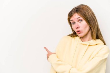 Beyaz arka planda izole edilmiş genç bir Rus kadın gülümsüyor ve boş alanda bir şeyler gösteriyor..